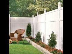 a chair sitting on top of a lush green field next to a white picket fence