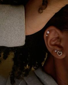 a close up of a person's ear with two piercings on it and one behind her head