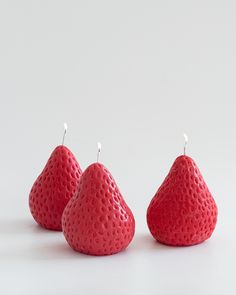 three red fruit shaped candles sitting next to each other