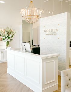 a white reception area with chandelier and chairs