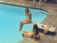 two women sitting on the edge of a swimming pool