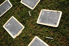 four chalkboards with writing on them laying in the grass