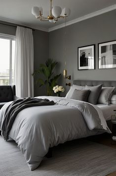 a bedroom with gray walls and white bedding in front of a large window that has two framed pictures on the wall