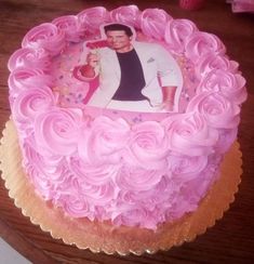 a pink cake with a picture of a man on it and roses around the edges