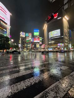 a city street at night with lots of lights and signs on the buildings in the background