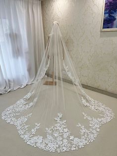 a white wedding veil with flowers on the bottom is hanging in front of a window