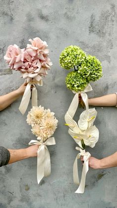 four different types of flowers are being held by hands