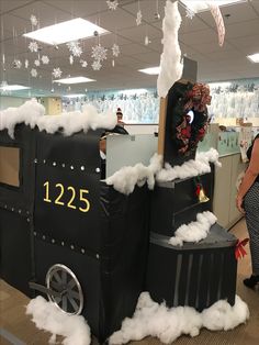 a woman standing next to a fake train with snow on it's roof and windows