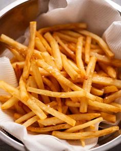 a metal bowl filled with french fries on top of a table