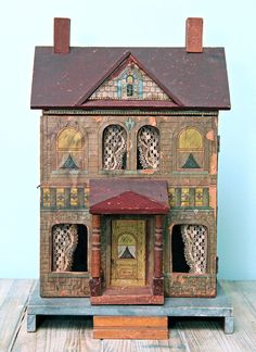 a doll house with lots of windows on top of a wooden table next to a blue wall