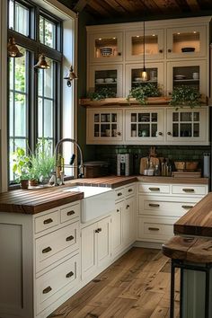 a kitchen filled with lots of white cabinets and wooden counter tops next to a window