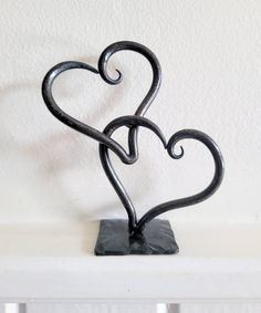 a metal heart sculpture sitting on top of a white shelf