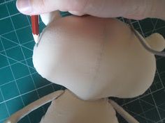 a person is making a doll out of paper and glues it with a red pen