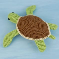 a crocheted turtle laying on top of a blue surface