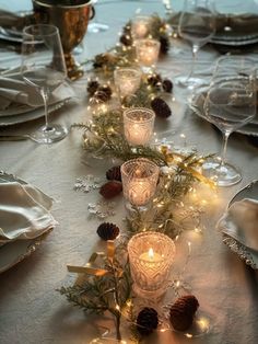 the table is set with candles and pine cones