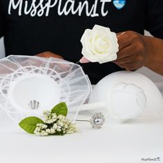 a man is holding a flower next to two white vases with flowers on them