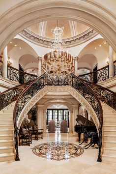 a grand piano sits in the center of this elegant entryway with chandelier