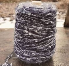 a spool of yarn sitting on top of a wooden table next to a tree