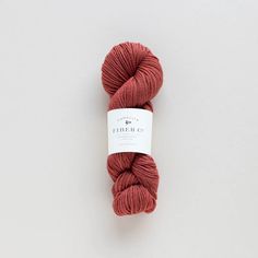 a skein of red yarn sitting on top of a white surface with a tag