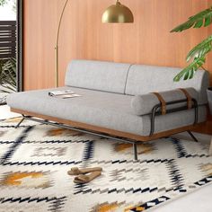 a couch sitting on top of a rug next to a lamp and potted plant