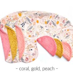 three pink and yellow bibs with floral designs on them, one is folded over the other