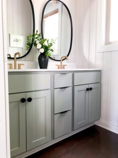 a bathroom with two round mirrors above the sink and white cabinets on either side of the mirror