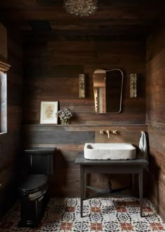 a bathroom with wood paneling and a white sink in the center, along with a black toilet