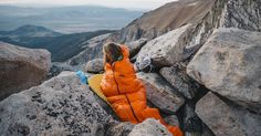 a woman sitting on top of a large rock next to a mountain covered in rocks