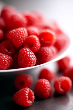 raspberries in a white bowl on a table