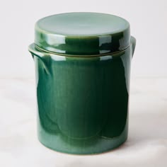 a green ceramic container sitting on top of a table