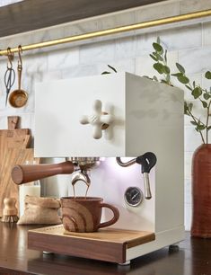 an espresso machine sitting on top of a wooden table next to a vase