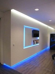 an empty room with white walls and blue lights on the wall is lit up by recessed lighting