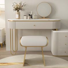 a white dressing table with gold trimmings and a round mirror on the wall