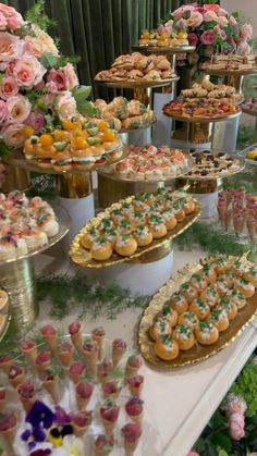 a table topped with lots of desserts covered in frosted pastries and flowers