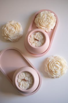 three pink containers with flowers in them on a white surface next to two smaller ones