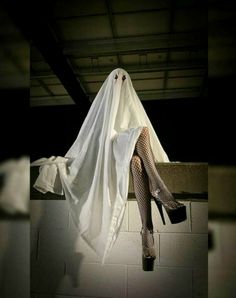 a woman dressed as a ghost hanging from the ceiling with her legs in the air