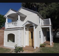 a white house with a brown door and balcony