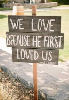 a wooden sign that says we love because he first loved us