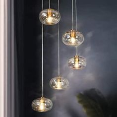 five clear glass globes hanging from a ceiling fixture in a room with dark walls