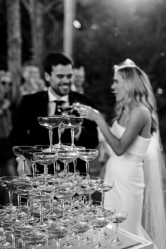 a man and woman standing next to each other with wine glasses in front of them