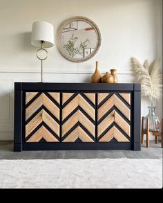 a black and wood sideboard with two vases sitting on top of it next to a clock