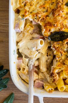 a casserole dish with ham, cheese and pasta in it on a wooden table