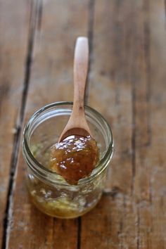 a jar filled with honey sitting on top of a wooden table next to a spoon