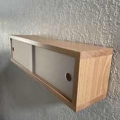 a wooden shelf mounted to the side of a wall with two glass doors on it