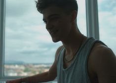 a young man standing in front of a window with his hand out to the side