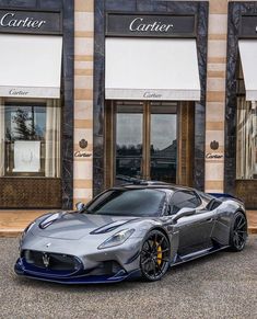 a silver and blue sports car parked in front of a building