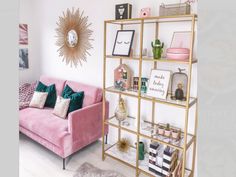 a living room with pink couches and gold shelving units on the wall above them