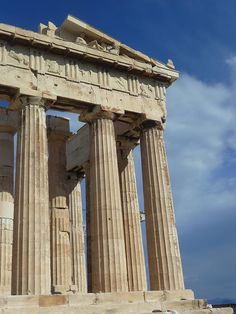 an ancient greek temple with columns against a blue sky