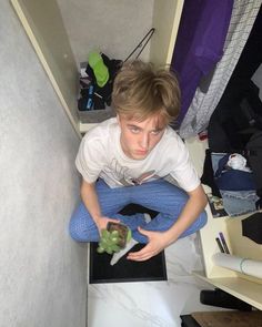 a young boy sitting on the floor holding a knife and some vegetables in his hands