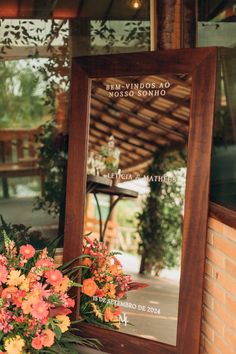 a mirror sitting on top of a table next to a vase with flowers in it